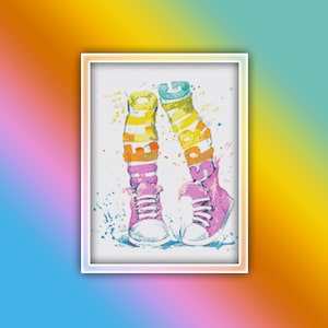 Puede incluir: Un par de zapatillas rosas con rayas de colores en las piernas. Las rayas deletrean la palabra "happy" en una pierna y "jump" en la otra. Las zapatillas están sobre un fondo blanco con salpicaduras de colores.