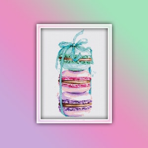 Op de afbeelding: Een stapel van vier kleurrijke macarons gebonden met een blauw lint. De macarons zijn lichtblauw, roze, paars en bruin.