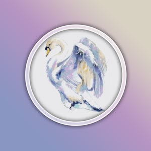 Könnte beinhalten: Ein weißer Schwan mit blauen und violetten Aquarellflügeln in einem runden Stickrahmen.