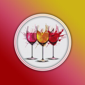 Puede incluir: Tres copas de vino con salpicaduras de color rojo, amarillo y rosa. Las copas son transparentes y tienen una base con tallo.