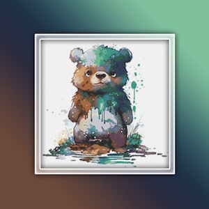 May include: A watercolour painting of a brown bear cub standing in a puddle of water. The bear is covered in green and blue paint splatters.
