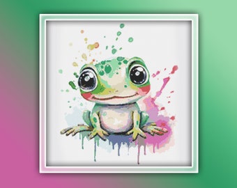Puede incluir: Una rana verde con ojos grandes y una sonrisa, sentada sobre un fondo blanco con salpicaduras de acuarela de colores.