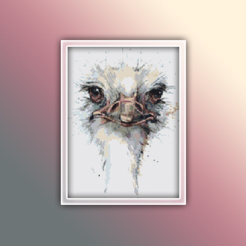 May include: A framed cross-stitch artwork depicting an ostrich's head. The piece uses brown, grey, and white threads to create a detailed image. The ostrich has dark brown eyes, and the frame is white. The artwork is a close-up view.