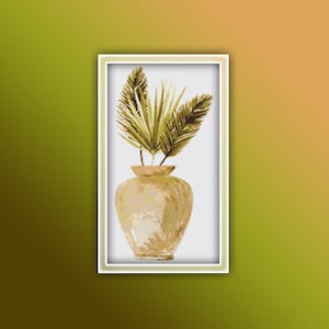 May include: A white ceramic vase with a brown glaze, filled with green leafy branches. The vase is sitting on a white background.