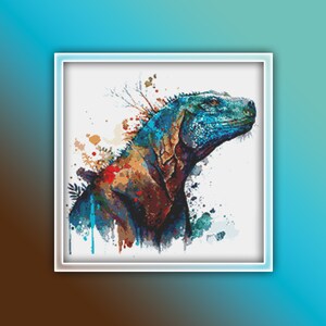 Puede incluir: Una pintura acuarela colorida de una iguana con tonos azules, rojos y marrones. La iguana está mirando hacia la derecha y tiene un fondo blanco.