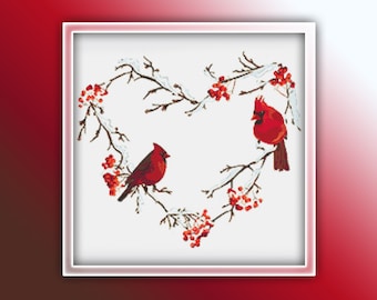 May include: Two red cardinals perched on snow-covered branches, forming a heart shape with red berries. The birds are facing each other, creating a romantic winter scene.