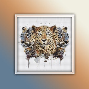 Op de afbeelding: Een aquarel schilderij van drie luipaard gezichten met blauwe en grijze aquarel spatten op de achtergrond.