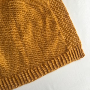 May include: A close-up of a mustard yellow knitted fabric with a ribbed edge.