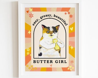 Peut inclure: Une illustration rétro colorée d'un chat tenant un bâton de beurre. Le texte dit "easy, greasy, beautiful" et "BUTTER GIRL".