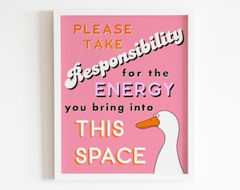 Peut inclure: Une affiche encadrée rose avec le texte "Veuillez prendre vos responsabilités pour l'énergie que vous apportez dans cet espace" en noir et orange. Une oie blanche avec un bec orange et des yeux noirs se trouve dans le coin inférieur droit de l'affiche.