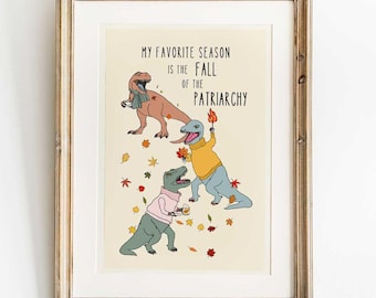 Peut inclure: Impression encadrée avec trois dinosaures de dessins animés portant des pulls et des écharpes, entourés de feuilles d'automne. Le texte dit : « MY FAVORITE SEASON IS THE FALL OF THE PATRIARCHY ».