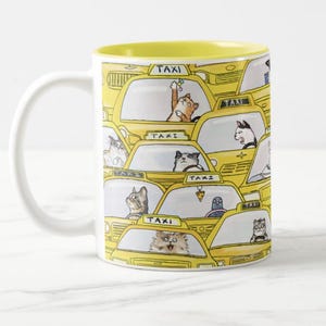 May include: A white ceramic mug with a yellow rim and a pattern of yellow taxis with cats driving them. The text "TAXI" is repeated on the mug.