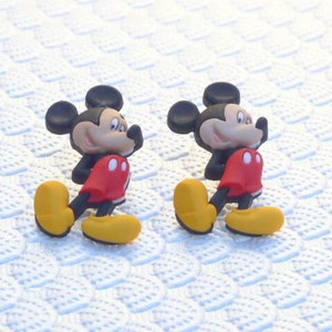 Może przedstawiać: Dwie czerwono-czarne postacie kresk&oacute;wkowego Myszki Miki w ż&oacute;łtych butach. Postacie są zwr&oacute;cone w r&oacute;żnych kierunkach.