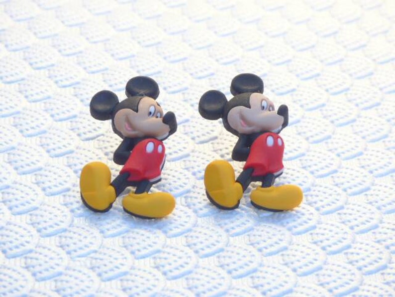 Może przedstawiać: Dwie czerwono-czarne postacie kresk&oacute;wkowego Myszki Miki w ż&oacute;łtych butach. Postacie są zwr&oacute;cone w r&oacute;żnych kierunkach.