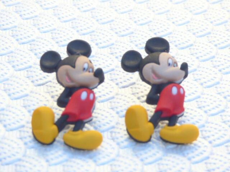 Może przedstawiać: Dwie czerwono-czarne postacie kresk&oacute;wkowego Myszki Miki w ż&oacute;łtych butach. Figurki stoją na białym tle.