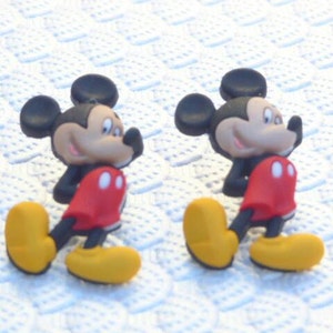 Może przedstawiać: Dwie czarne i czerwone figurki Myszki Miki z ż&oacute;łtymi butami. Figurki stoją na białym tle.