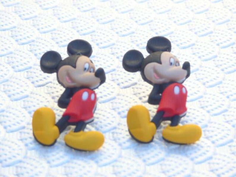 Może przedstawiać: Dwie czarne i czerwone figurki Myszki Miki z ż&oacute;łtymi butami. Figurki stoją na białym tle.