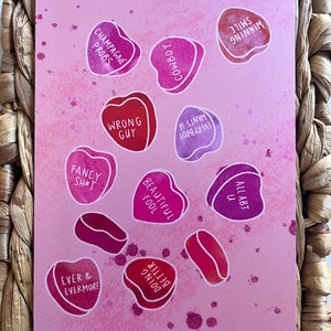 May include: Pink background with various heart-shaped candies with different sayings on them. The sayings include "Champagne probs", "Cowboy", "Wrong guy", "Everybody wants u", "Beautiful fool", "Fancy sh*t", "All abt u", "Better doing", "Ever & evermore", and "Winning smile".
