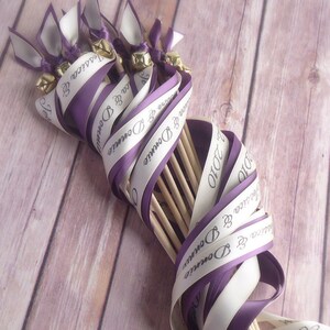 May include: A bundle of purple and white ribbon wands with bells and the text "Jessica & Donnie 2010" printed on them.
