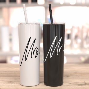 Puede incluir: Dos vasos de acero inoxidable con tapas y pajitas. El vaso de la izquierda es blanco con texto negro que dice "Sra.". El vaso de la derecha es negro con texto blanco que dice "Sr."