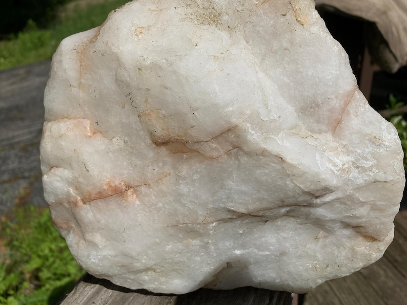 May include: A large, rough quartz rock, predominantly creamy white with delicate tan and peach-coloured veining. The surface has a textured appearance, with natural ridges and variations. Likely a decorative or collectible item, possibly for display.