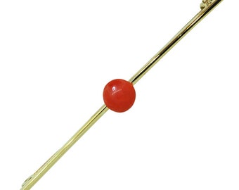 May include: A gold bar pin with a single red coral bead in the center.