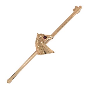 May include: A gold-toned tie tack featuring a horse head design. The horse has a red gemstone eye.