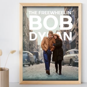 Peut inclure: Une affiche vintage avec une photo en noir et blanc de Bob Dylan et une femme marchant dans une rue de la ville. L'affiche porte le texte "The Freewheelin' Bob Dylan" en lettres blanches.