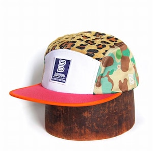 May include: A five-panel cap featuring a leopard print top, camouflage side panels, and a white front panel with a blue and white Boojuu logo patch that reads A TRIBE OF OUR OWN. The cap has a flat pink brim with an orange edge and white stitching.