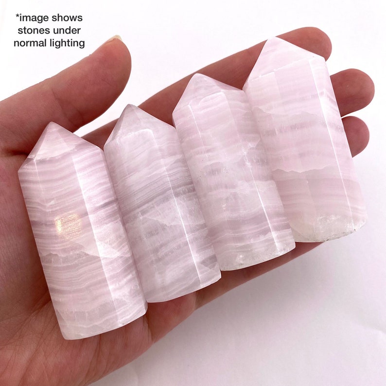 May include: Five pink calcite crystal points with white striations. The points are arranged in a row, with the largest point at the top and the smallest point at the bottom.