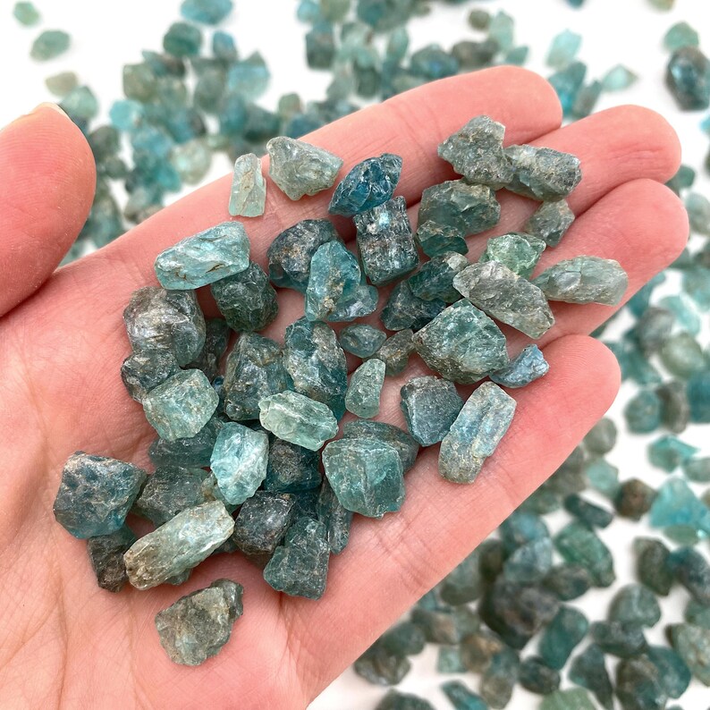 May include: A handful of teal blue apatite crystal chips. The chips are rough and have a natural, unpolished look.