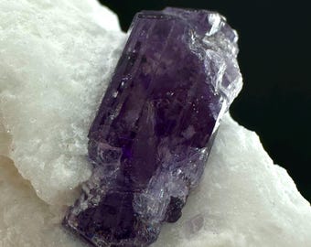 Cristal de escapolita púrpura sobre matriz de feldespato, muestra mineral.