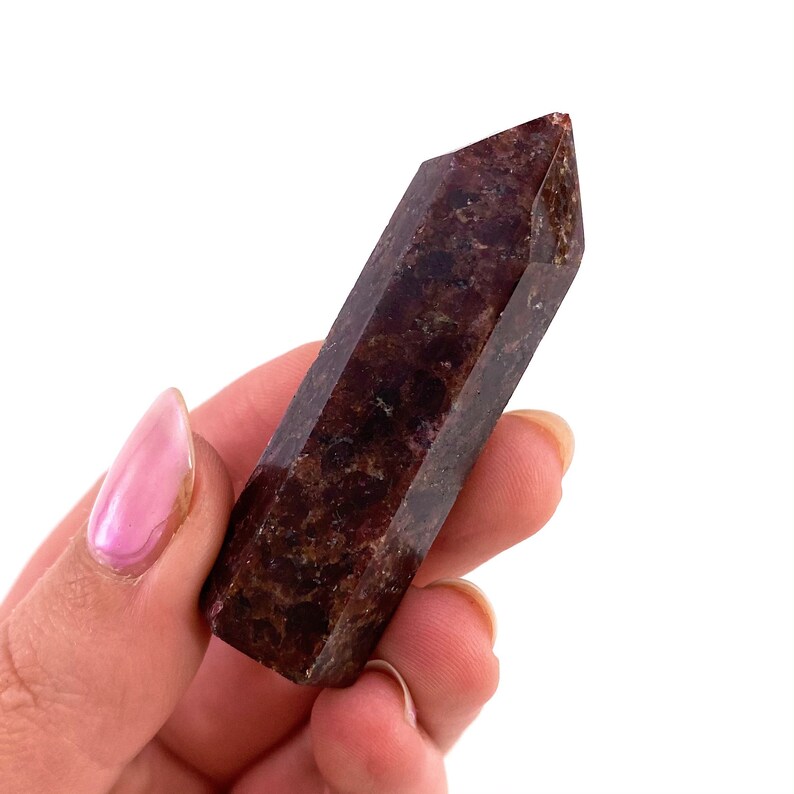 May include: A dark red, brown, and black crystal point with a pointed tip. The crystal is smooth and polished.