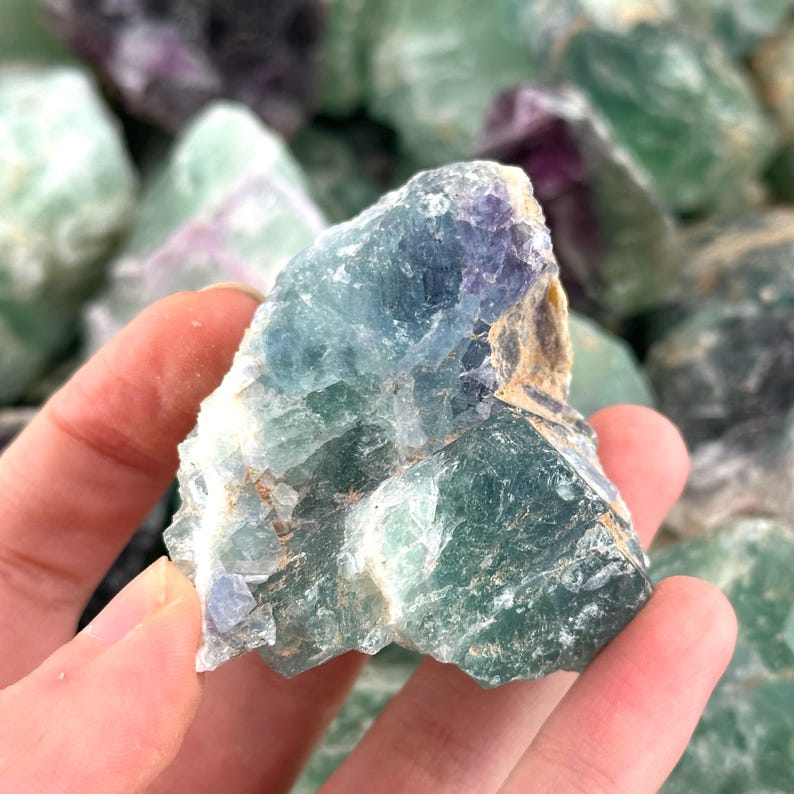 K&ouml;nnte beinhalten: Ein gro&szlig;er, rauer, gr&uuml;ner Fluoritkristall mit violetten und wei&szlig;en Akzenten. Der Kristall hat ein nat&uuml;rliches, rohes Aussehen und ist ein wundersch&ouml;nes Beispiel f&uuml;r dieses Mineral.