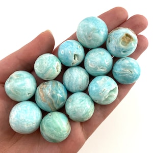 May include: A collection of 12 smooth, round, blue and green celestite spheres. The spheres are polished and have a natural, swirling pattern.