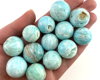 May include: A collection of 12 smooth, round, blue and green celestite spheres. The spheres are polished and have a natural, swirling pattern.