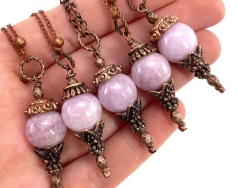 May include: Four delicate necklaces with pale lavender gemstone pendants and ornate copper accents. Each pendant features a detailed copper design and a smooth, round gemstone.
