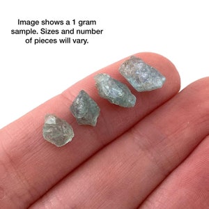 May include: Five small, rough, green aquamarine crystals on a hand. Image shows a 1 gram sample. Sizes and number of pieces will vary.