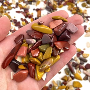 May include: A collection of polished, multi-colored, natural stones in shades of red, yellow, and brown. The stones are smooth and have a variety of shapes and sizes.
