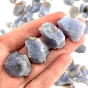 May include: A collection of blue chalcedony tumbled stones. The stones are various sizes and shapes, with a smooth, polished finish.