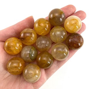 K&ouml;nnte beinhalten: Eine Sammlung von 12 glatten, polierten, goldenen Citrin-Kugeln. Die Kugeln sind in verschiedenen Gelb- und Braunt&ouml;nen gehalten, einige haben eine klare, glasartige Optik.