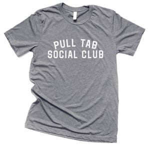 May include: A heather gray crew neck t-shirt with the text "PULL TAB SOCIAL CLUB" in white block letters. The shirt is made of a soft material and is displayed on a white background.