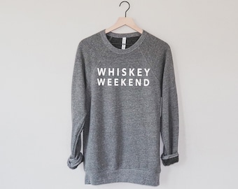 Può includere: Una felpa grigia con la scritta "WHISKEY WEEKEND" stampata in bianco sul davanti.