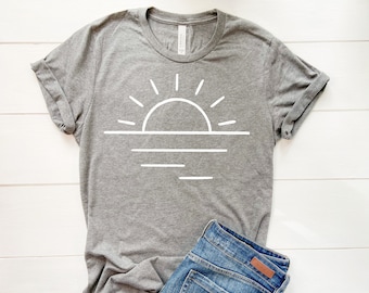 Peut inclure: Un t-shirt gris chiné avec un contour blanc d'un soleil couchant sur l'océan.