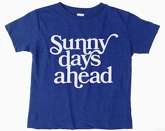 Może przedstawiać: Koszulka z krótkim rękawem w kolorze królewskiej niebieskości z napisem "Sunny days ahead" w kolorze białym.