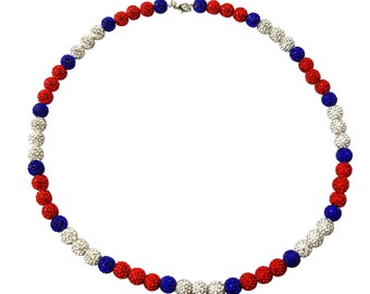 May include: A red, white and blue beaded necklace with a silver clasp. The beads are small and round, and they are arranged in a repeating pattern.