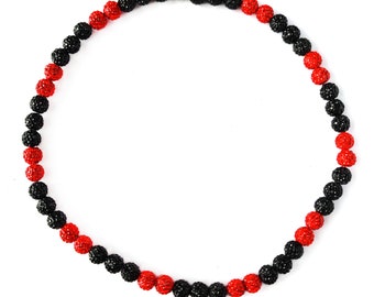 May include: A black and red beaded necklace with alternating colours. The necklace is made of small, round beads that are covered in tiny crystals.