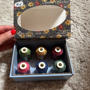 May include: A box of six mini-king spools of 100% Egyptian cotton quilting thread in assorted colors. The box is labeled "Summer Collection" and "Thimbleberries by Lynette Jensen".