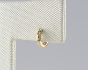 May include: A gold hoop earring with a smooth, polished finish. The earring is displayed on a white stand.