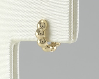 May include: Gold hoop earrings with a textured, beaded design.